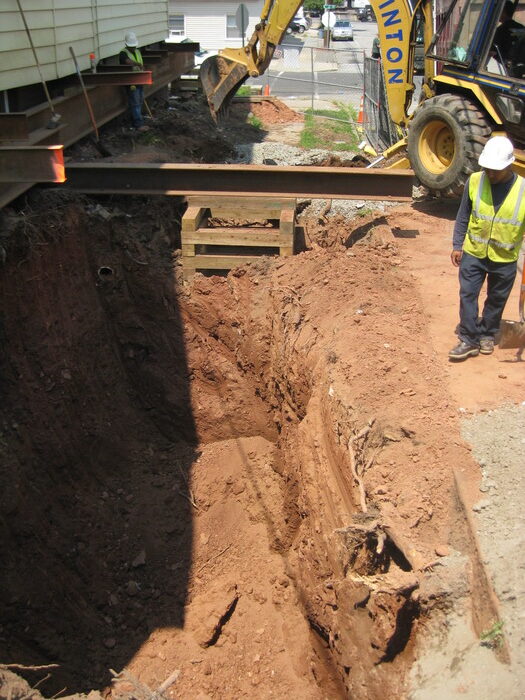 Construction workers near an excavation site with an I-beam support structure