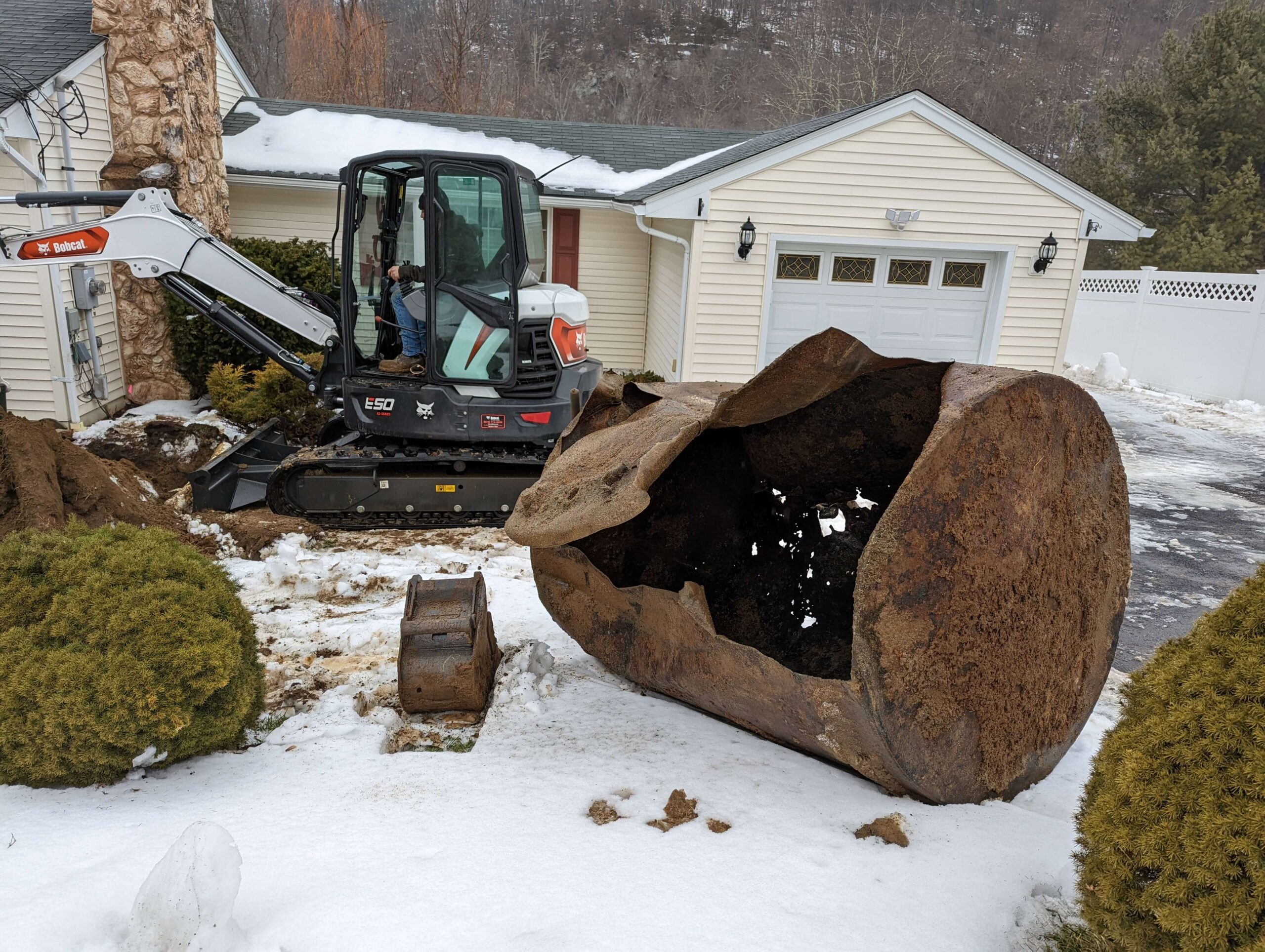 Excavator removing a rusted tank from the ground