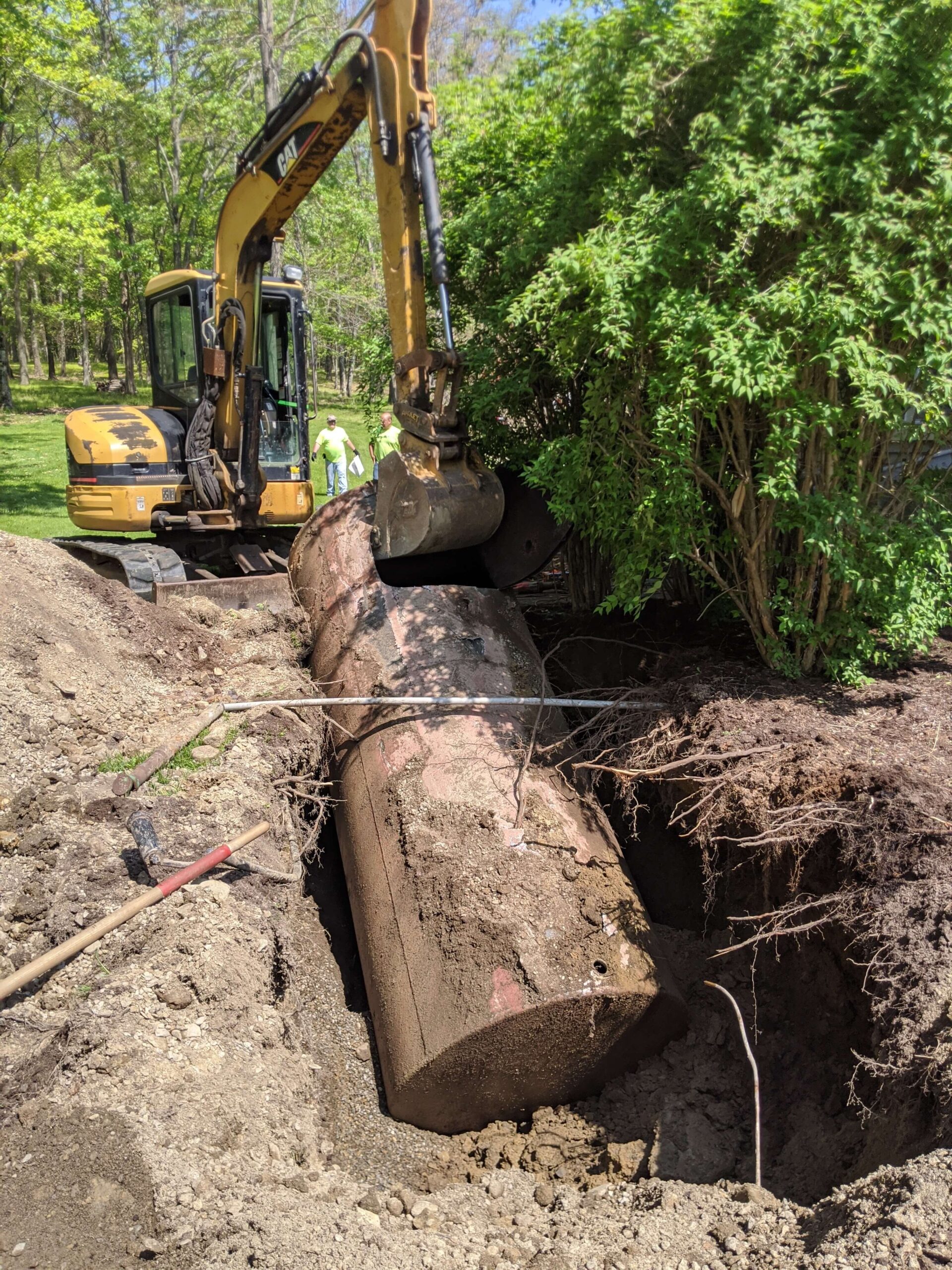 Excavator removing a tank from the ground during excavation work