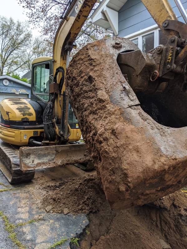Excavator lifting a large tank from the ground